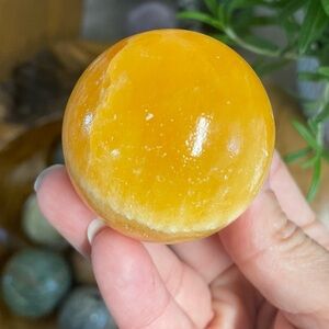 Orange calcite polished crystal sphere with stand